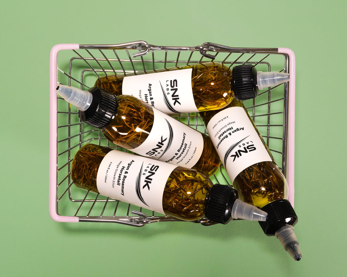 SNK Labs Hair Growth Elixir bottles in a woven basket, a botanical oil containing turmeric root extract