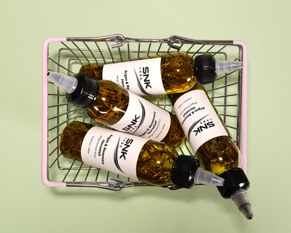 SNK Labs Hair Growth Elixir bottles in a woven basket, a lightweight oil for reducing hair breakage
