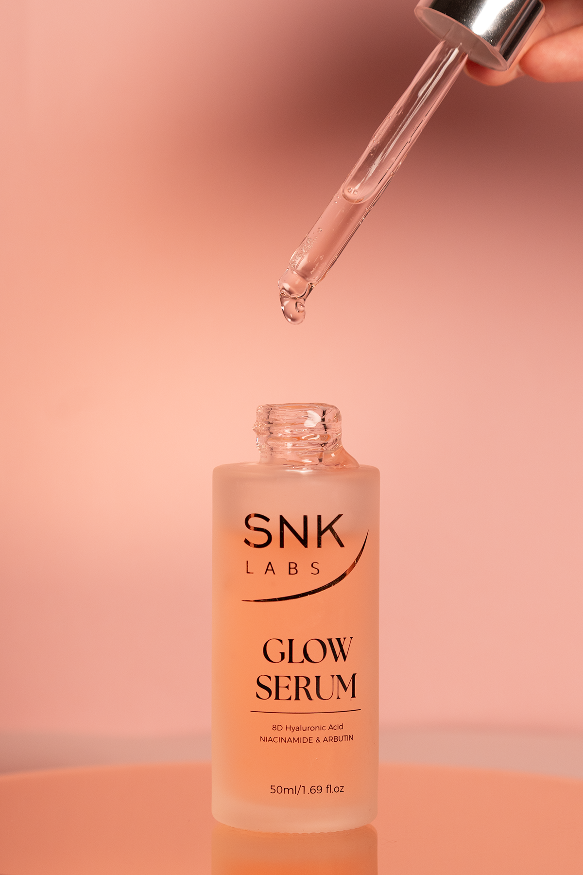A drop of SNK Labs Glow Serum on the dropper tip, formulated with rice ferment filtrate